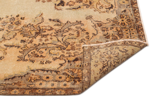 Load image 1 in gallery view. Tan and brown vintage-style rug with a distressed floral medallion pattern and a folded corner, on a white background.