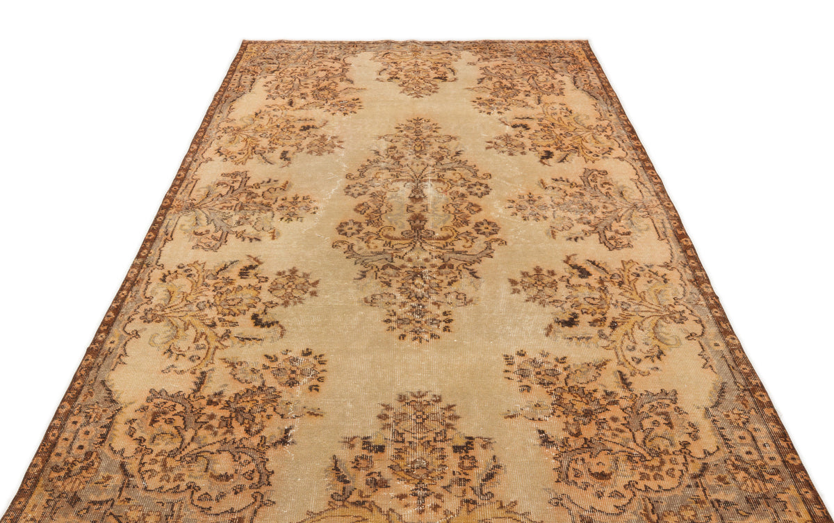 Distressed beige and brown vintage-style rug with a central floral medallion and ornate border pattern.