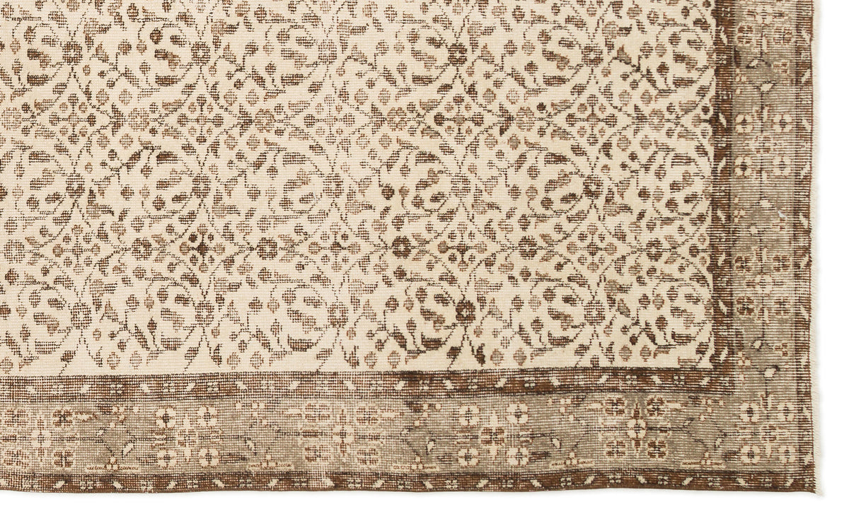Cream and brown rug with a repeating floral lattice pattern and a wide, detailed border.