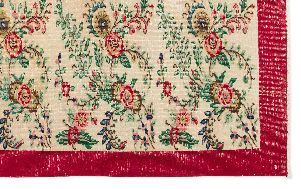 Cream rug with a floral pattern in red, green, and blue, featuring a wide red border.