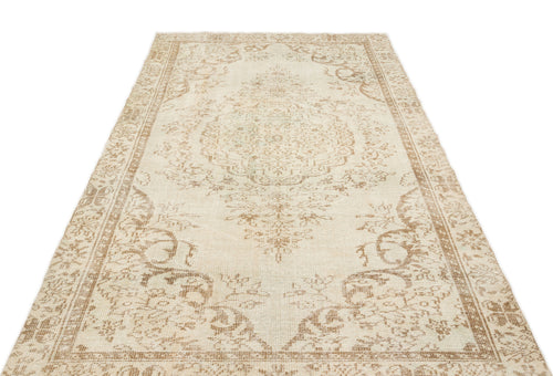 Load image 1 in gallery view. Beige and cream vintage-style rug with a central floral medallion and ornate border on a white background.