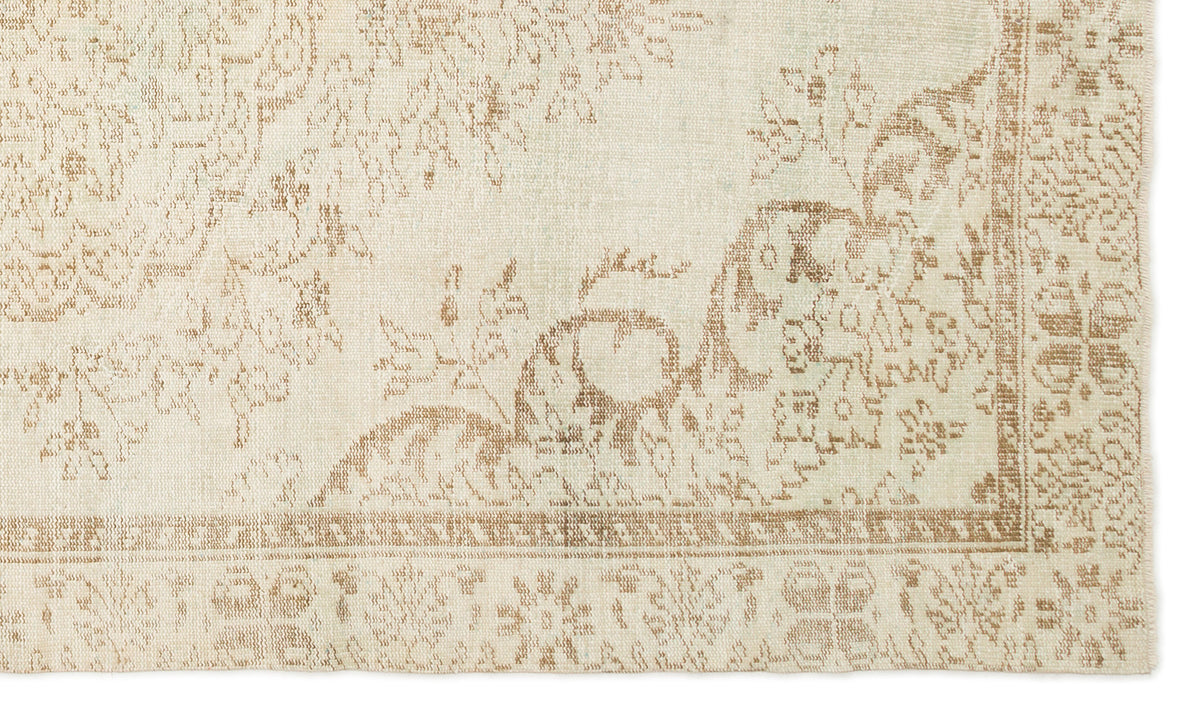 Cream and beige rug with a distressed floral medallion pattern and a geometric border.