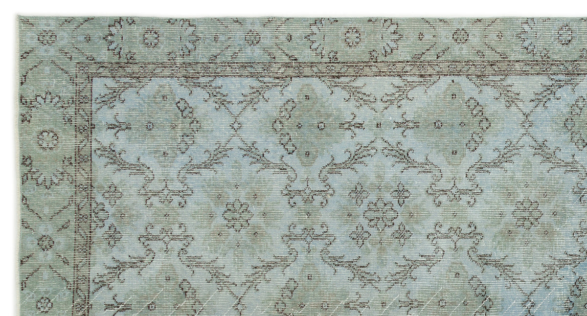 Light blue and sage green rug with a distressed traditional floral medallion pattern and a dark brown border.
