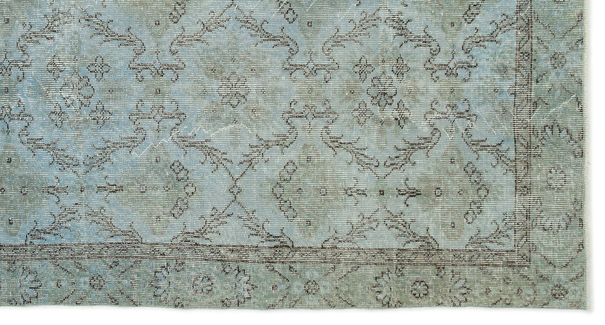 Light blue and sage green distressed rug with a faded traditional floral medallion pattern and a thin border.