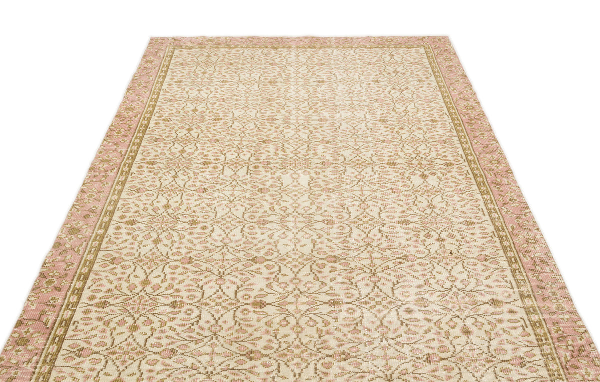 Cream, pink, and tan rug with an intricate floral medallion pattern and a wide decorative border.