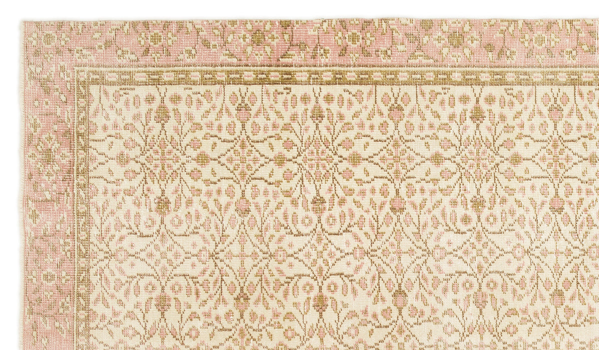 Cream and pink rug with a repeating floral medallion pattern and a geometric border.