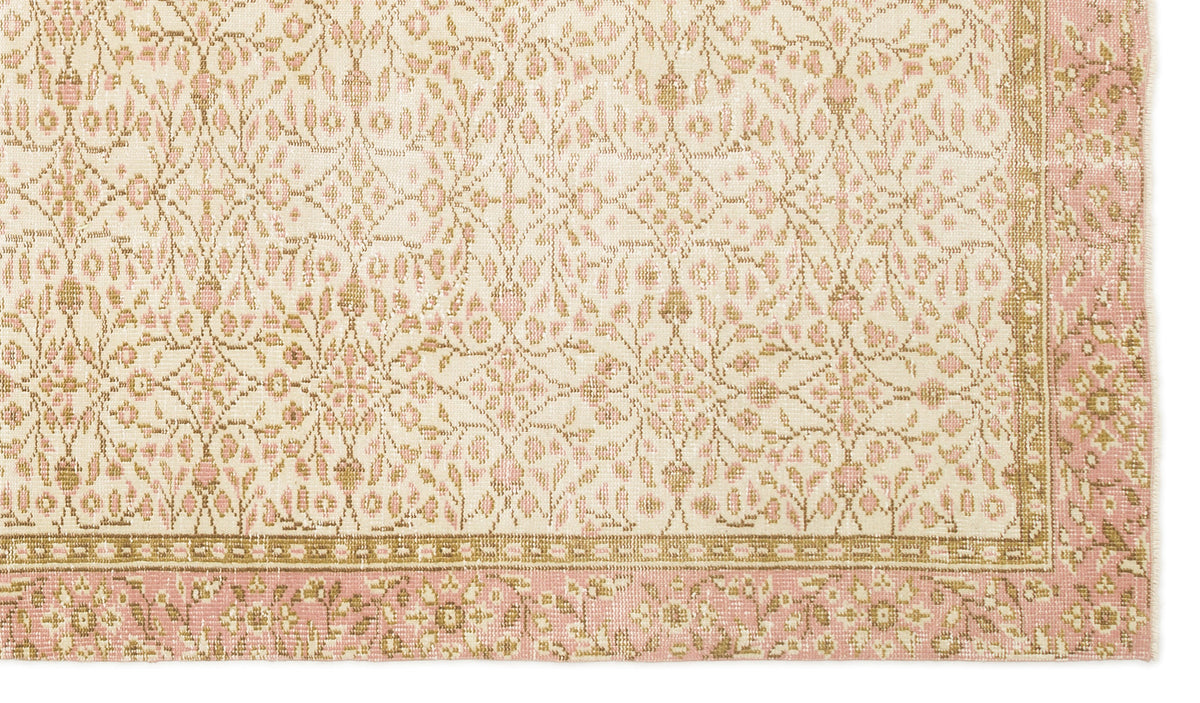 Cream and pink rug with a repeating floral medallion pattern and a decorative border.
