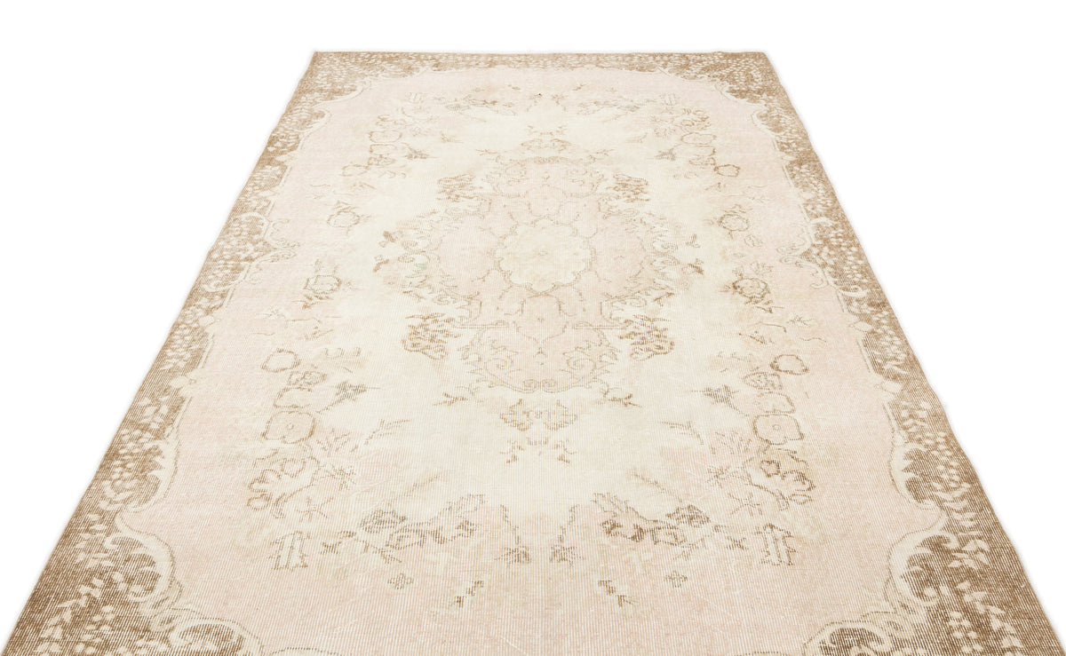 Beige and cream vintage-style rug with a faded central floral medallion and ornate border on a white background.