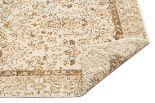 Load image 1 in gallery view. Beige and cream distressed rug with a traditional floral medallion pattern and a folded corner on a white background.