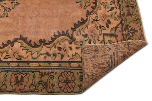 Load image 1 in gallery view. Terracotta and olive green vintage-style rug with a floral medallion border, shown with a corner folded over.