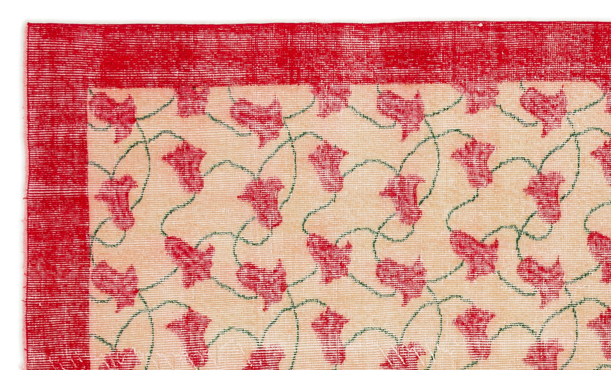 Cream rug with a red border and a repeating pattern of red floral motifs connected by thin green vines.
