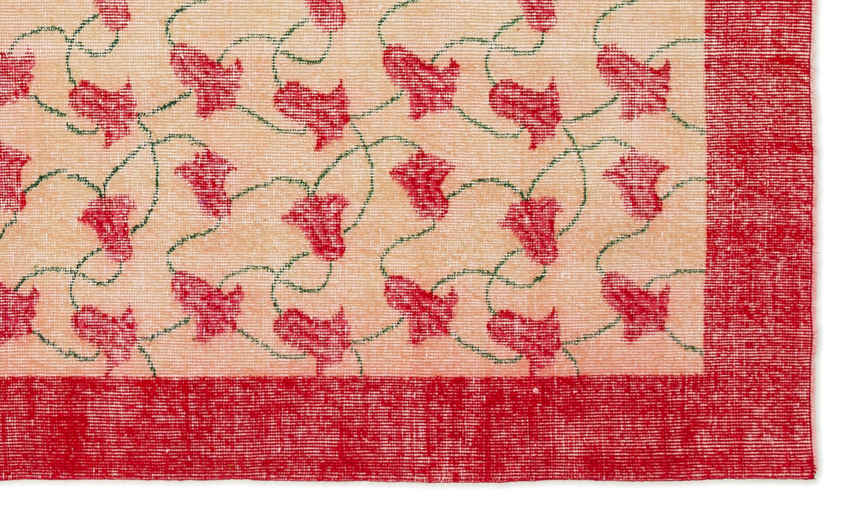 Peach rug with a repeating pattern of red floral motifs connected by thin green vines and a solid red border.