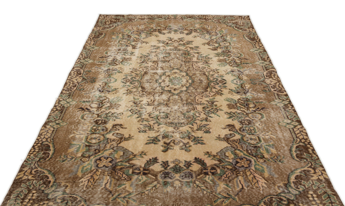 Distressed brown and beige vintage-style rug with a central floral medallion and ornate border.
