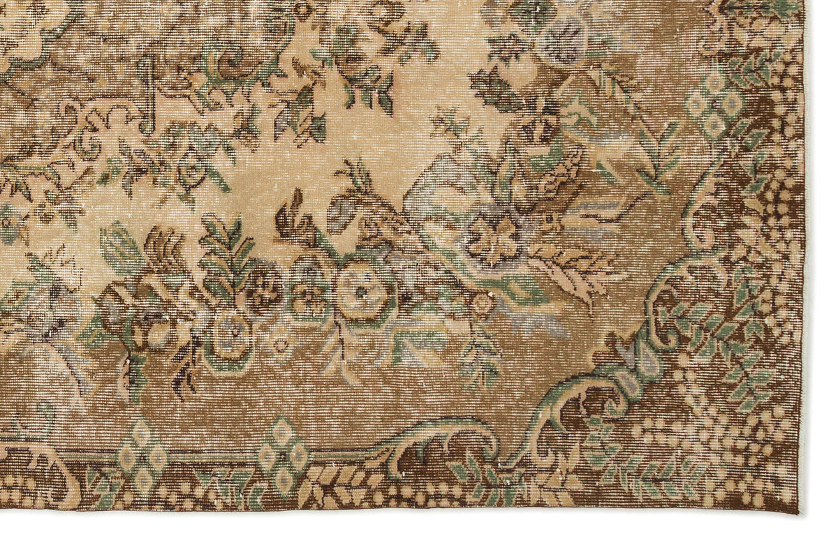 Distressed tan and brown rug with a faded floral medallion pattern and sage green accents.