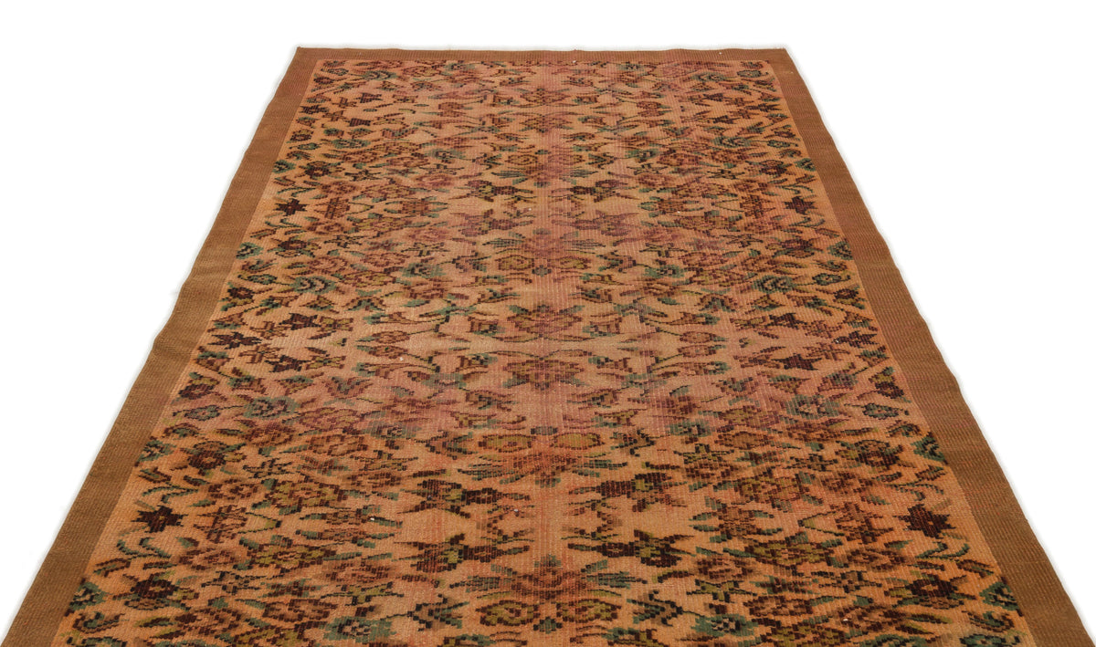 Terracotta and green vintage-style rug with a repeating floral medallion pattern and a solid brown border.