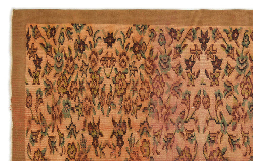 Load image 1 in gallery view. Peach-toned rug with a solid brown border and an all-over repeating floral motif in muted green, brown, and dark red.