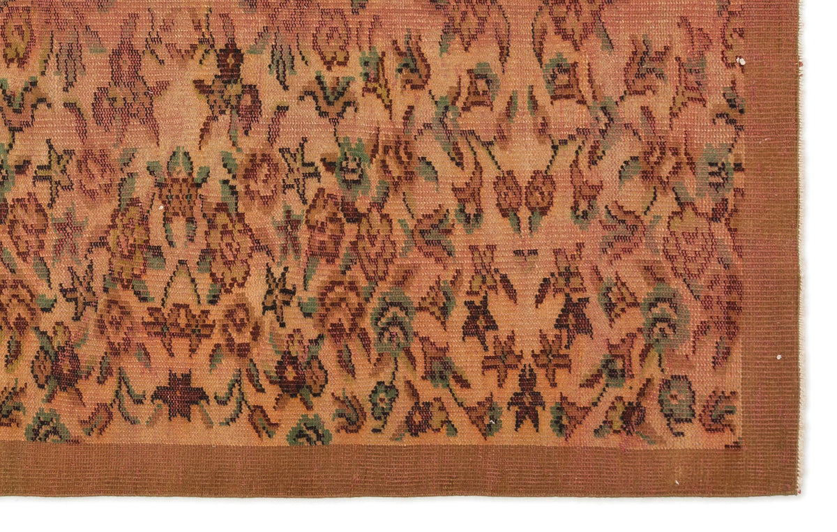 Terracotta rug with a faded floral pattern in green and brown, featuring a solid dark brown border.