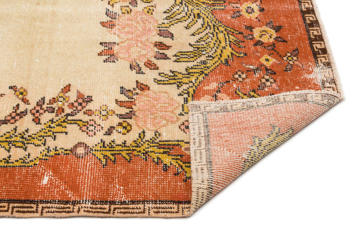 Load image 1 in gallery view. Distressed cream and rust-orange rug with a floral medallion pattern and a folded corner showing the woven backing.