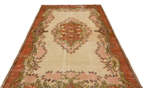 Load image 1 in gallery view. Distressed beige rug with a central rust-colored medallion and floral border in shades of pink, green, and brown.