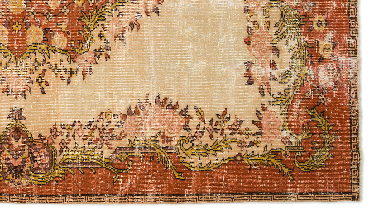 Distressed terracotta and beige rug with a floral medallion pattern and a geometric border.