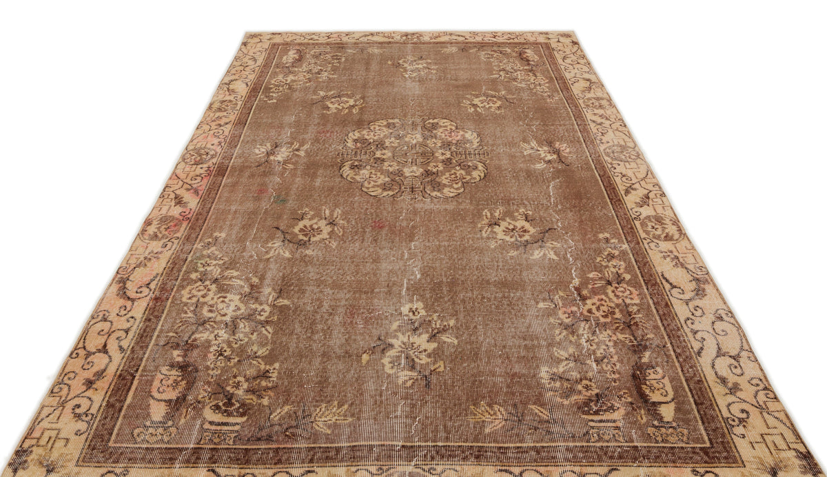 Brown vintage-style rug with a central floral medallion, distressed texture, and a decorative border.
