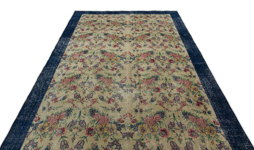 Load image 1 in gallery view. Beige rug with a distressed floral pattern in red, yellow, and blue, featuring a wide navy blue border.