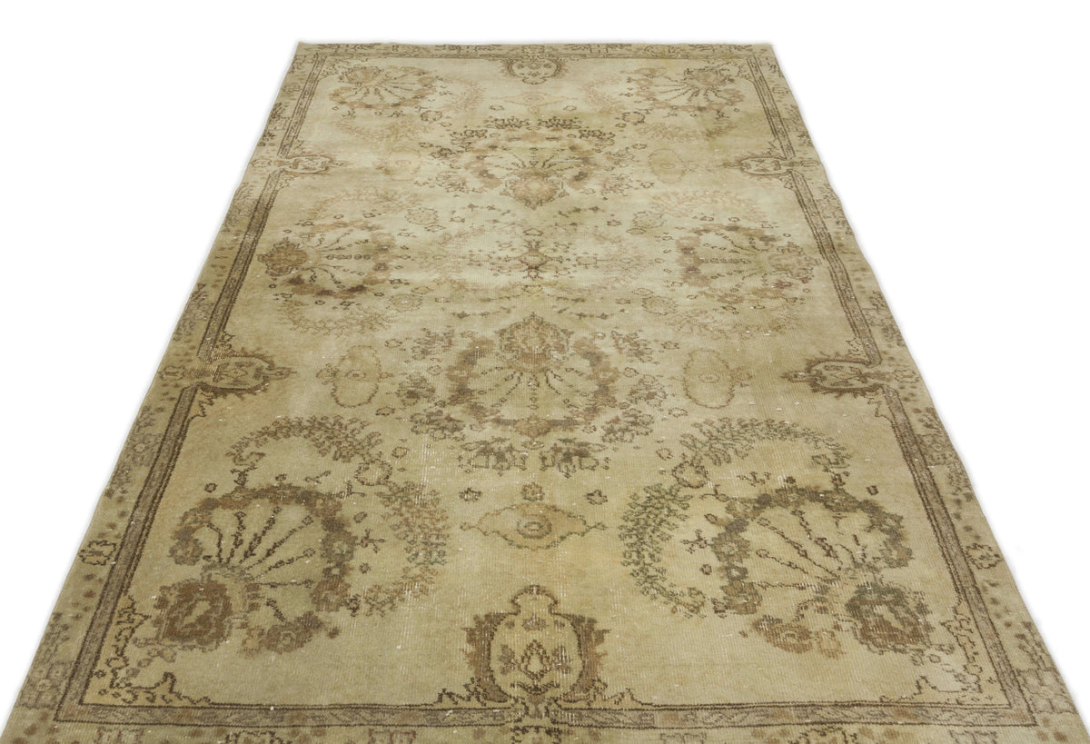 Beige and brown distressed vintage-style rug with a faded floral medallion pattern and a decorative border.