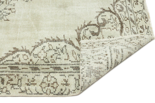 Load image 1 in gallery view. Sage green and brown distressed rug with a traditional floral medallion pattern, shown with a folded corner.