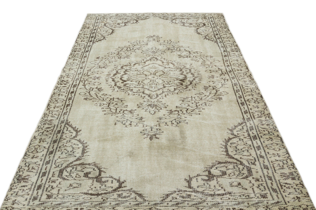 Beige and brown vintage-style rug with a central floral medallion and ornate border on a white background.