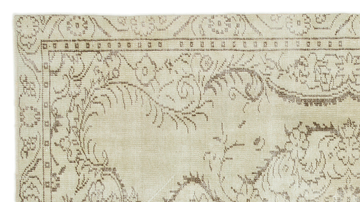 Beige and taupe rug with a distressed floral vine pattern and a geometric border.