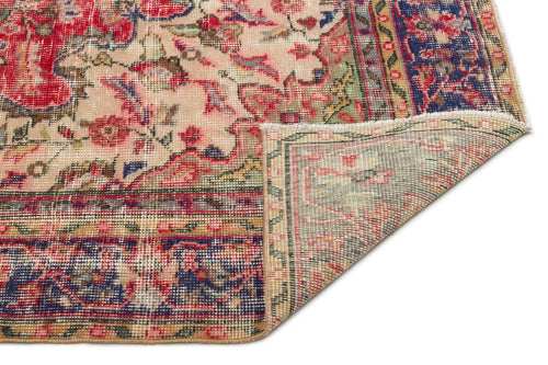 Load image 1 in gallery view. Distressed Persian-style rug with red, blue, and beige floral patterns, shown with a corner folded over on white.