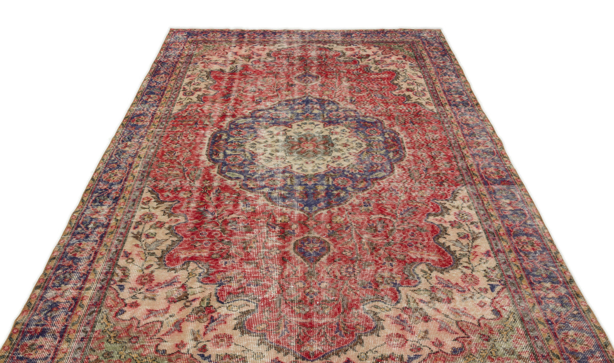 Distressed red and blue vintage-style rug with a central floral medallion and ornate border on a white background.
