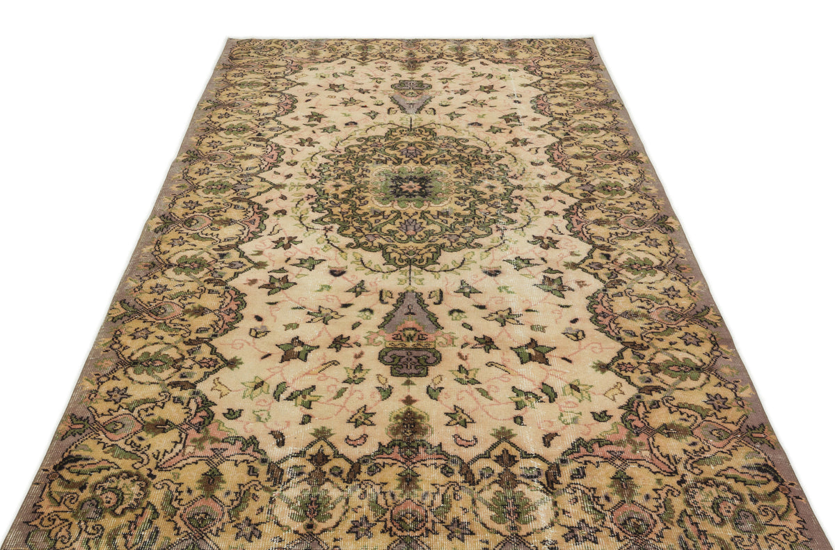Beige vintage-style rug with a central floral medallion and intricate botanical motifs in green, pink, and charcoal.