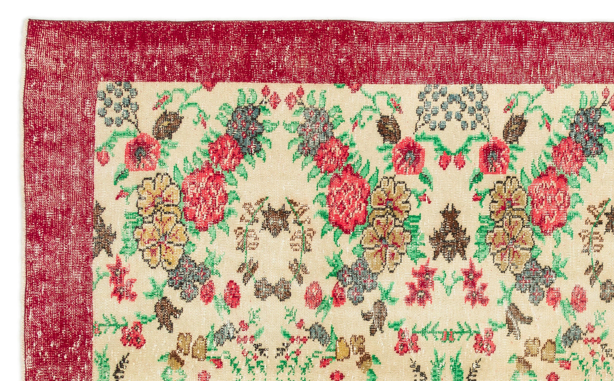 Cream rug with a distressed red border and a multi-colored floral pattern in red, green, and brown.