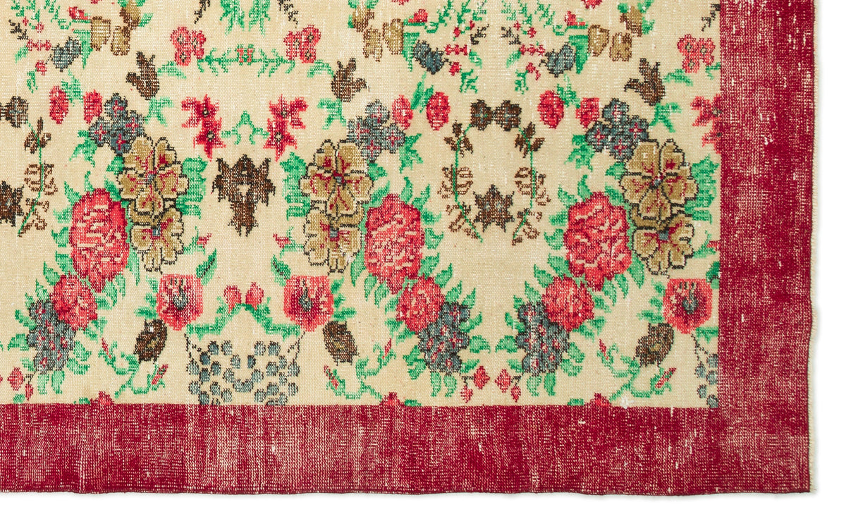 Cream rug with a floral pattern in red, green, and brown, featuring a wide solid red border.