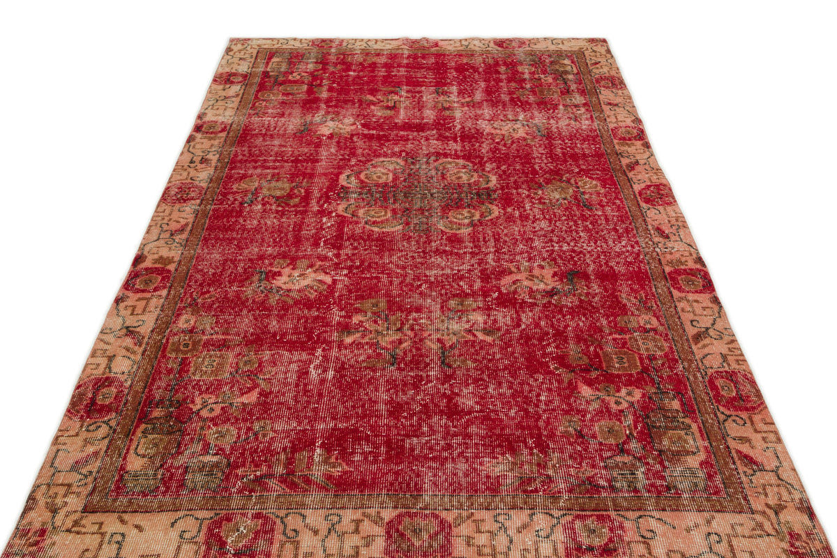 Distressed red and beige vintage-style rug with a central floral medallion and ornate border on a white background.