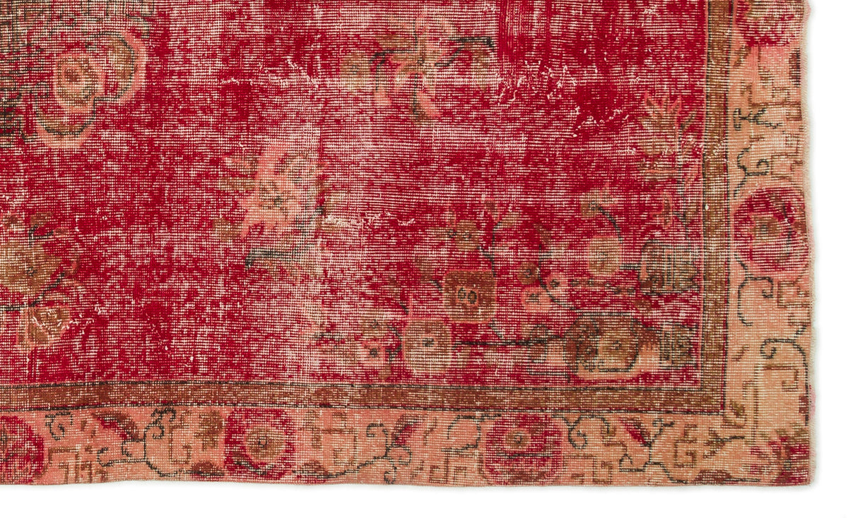 Distressed red vintage rug with faded floral patterns and a tan border, isolated on a white background.