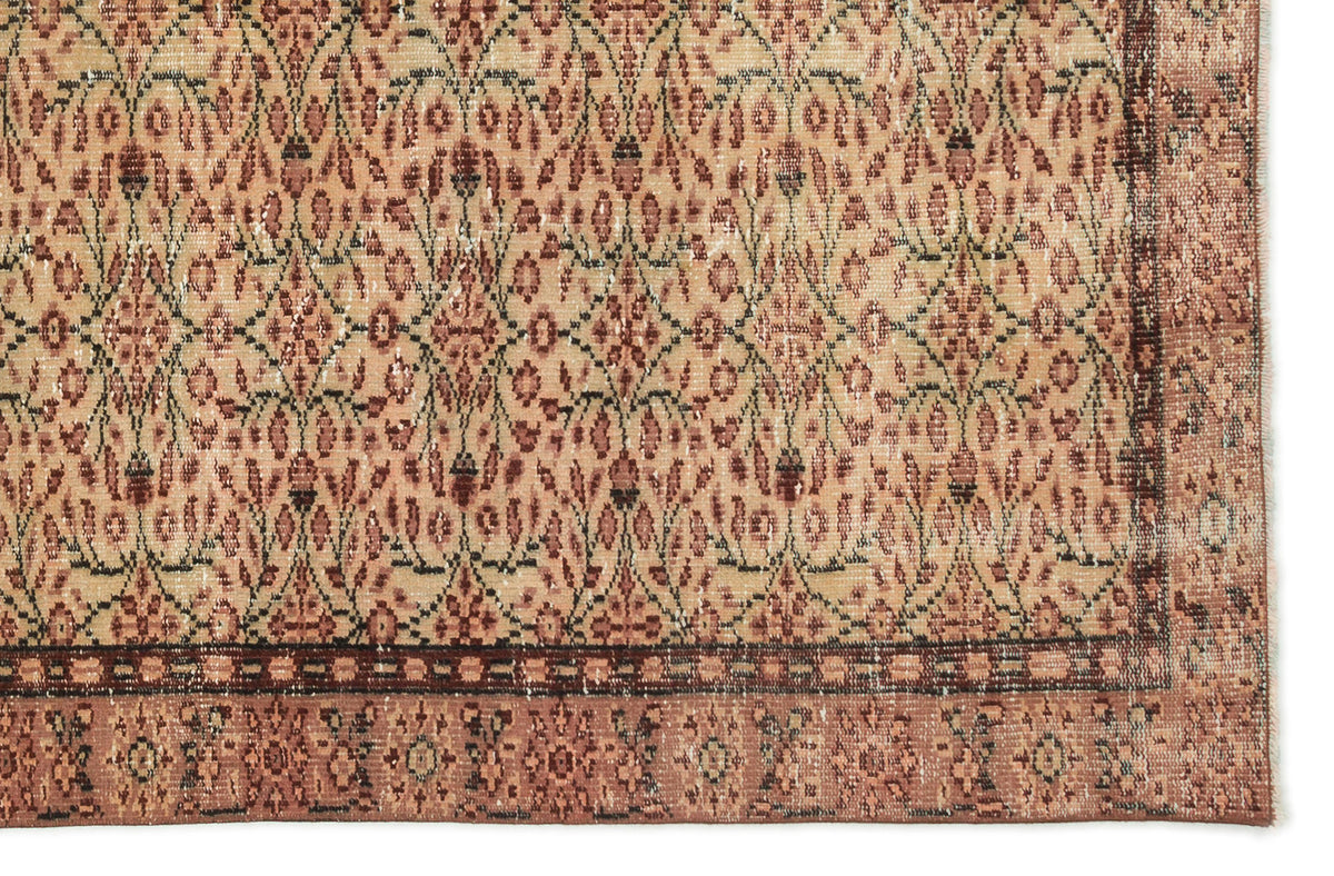 Tan and terracotta vintage-style rug with a repeating floral lattice pattern and a decorative border.