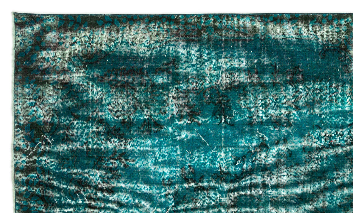 Teal and black distressed rug with a faded, vintage-inspired floral pattern.