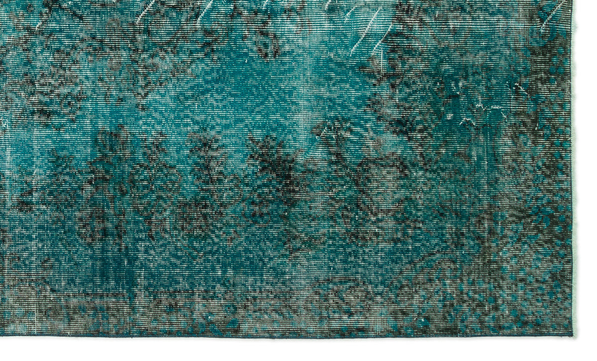 Teal and black distressed rug with a faded, abstract vintage pattern.