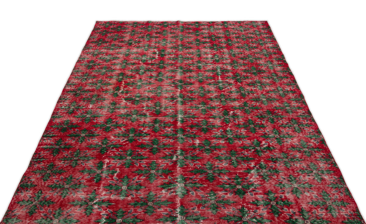 Red and green distressed rug with an all-over geometric floral pattern on a white background.