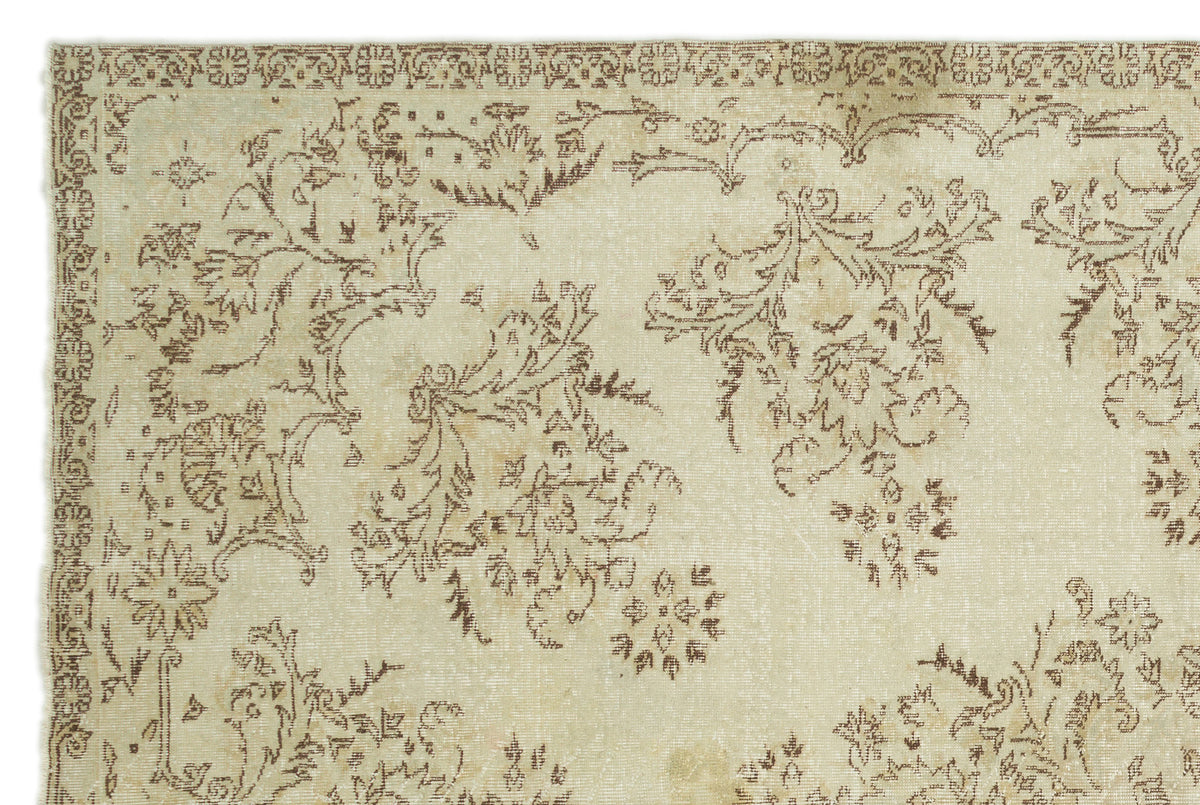 Beige and brown vintage-style rug with a distressed floral pattern and a decorative border.