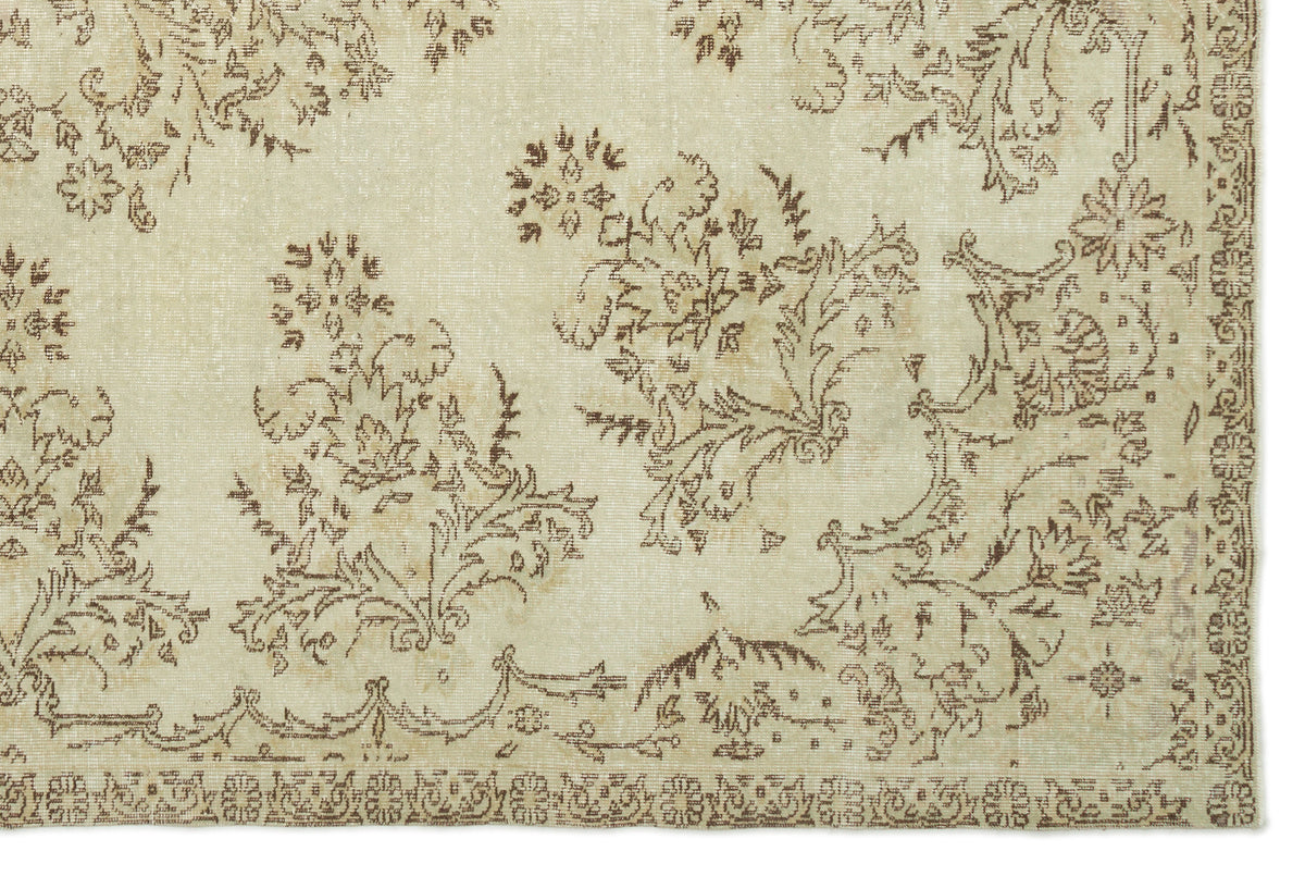 Beige and brown vintage-style rug with a distressed floral pattern and a decorative border.