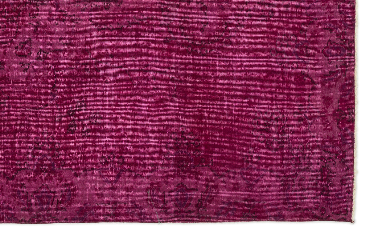 Magenta overdyed vintage rug with a distressed, faded traditional floral pattern.