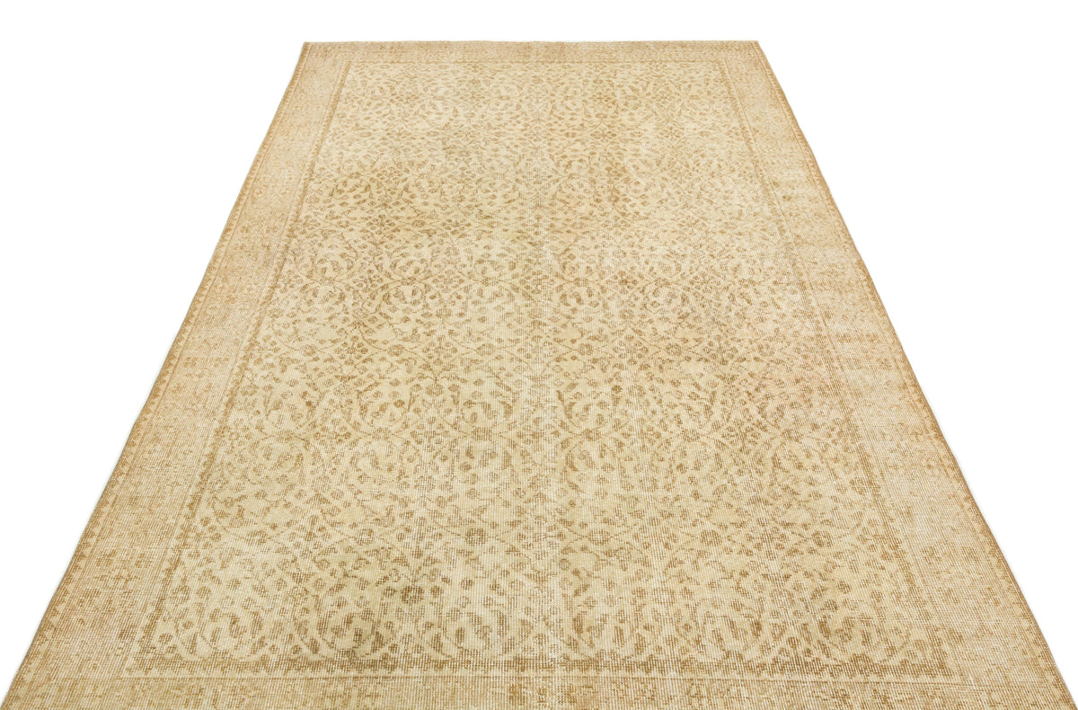 Beige and tan vintage-style rug with an intricate, faded floral medallion pattern and a bordered edge.