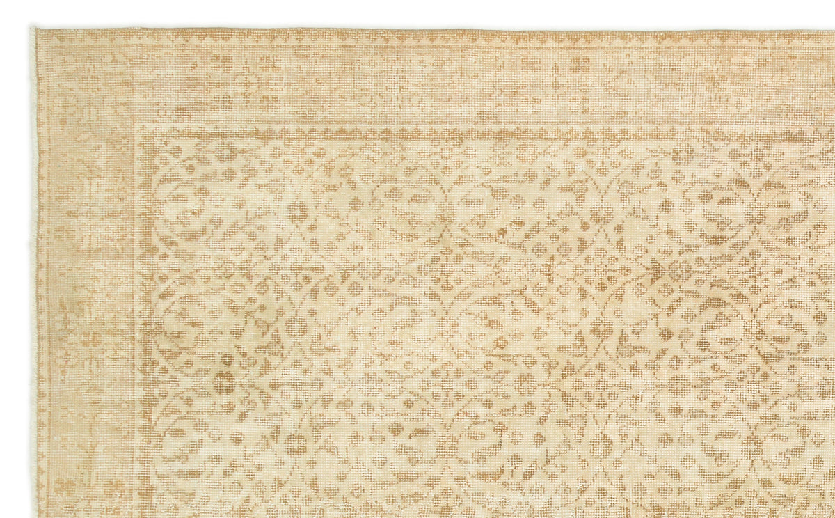 Beige and tan rug with a faded, traditional floral medallion pattern and a decorative border.