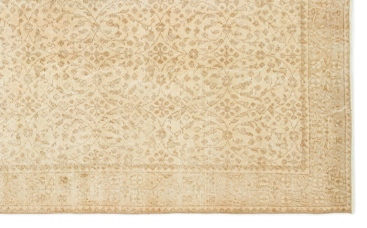 Beige and tan rug with a distressed, repeating floral medallion pattern and a decorative border.