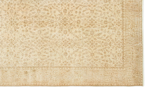 Load image 1 in gallery view. Beige and tan rug with a distressed, repeating floral medallion pattern and a decorative border.