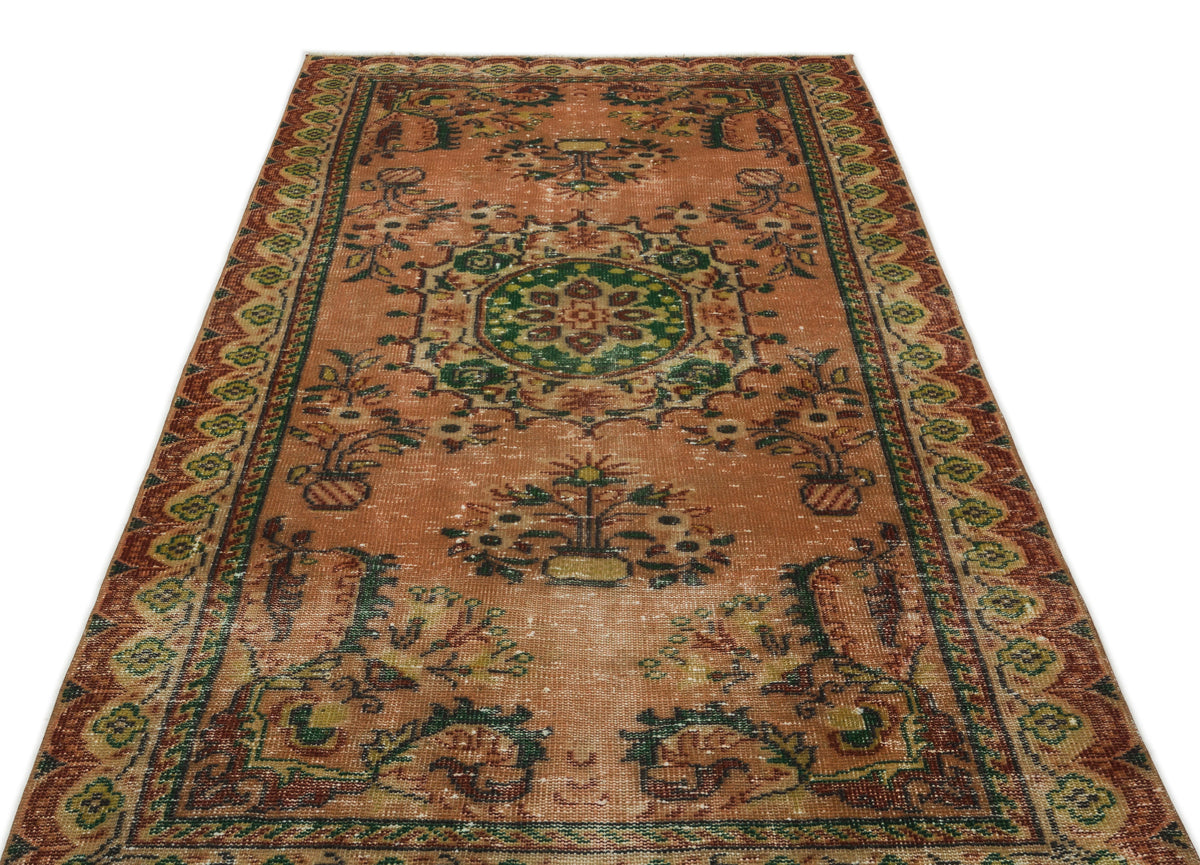 Terracotta vintage-style rug with a central green floral medallion and ornate geometric border on a white background.