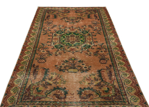 Load image 1 in gallery view. Terracotta vintage-style rug with a central green floral medallion and ornate geometric border on a white background.